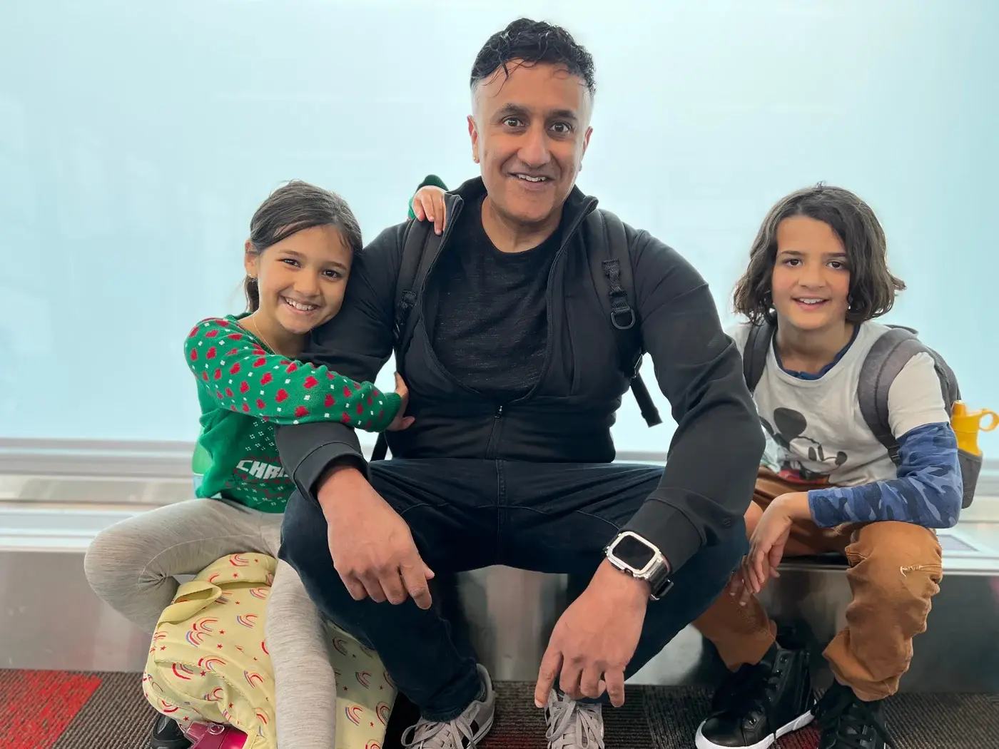 Neo smiling, seated between two children
